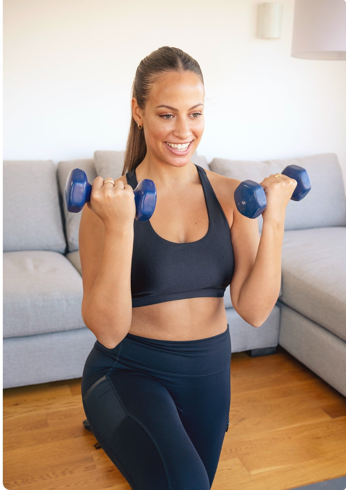Smiling women exercising with dumbbells in her living room
