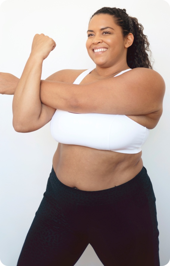 woman smiling and performing a left arm over body stretch